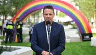 Rafał Trzaskowski podczas wystąpienia w Warszawie przy mikrofonie, w tle kolorowy łuk symbolizujący wydarzenie miejskie