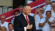 Prezydent RP Karol Nawrocki podczas wystąpienia na dziedzińcu Pałacu Prezydenckiego w pierwszą rocznicę zaprzysiężenia. W tle scena, publiczność oraz biało-czerwone flagi.