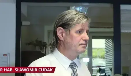 Dr hab. Sławomir Cudak w białej koszuli i krawacie podczas próby wejścia do gabinetu w Akademii Wymiaru Sprawiedliwości
