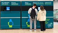 Dwoje młodych ludzi oddaje plastikowe butelki do dużego, niebiesko-zielonego butelkomatu w markecie Lidl