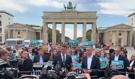 Konferencja prasowa polityków CDU przed Bramą Brandenburską w Berlinie w otoczeniu dziennikarzy i zwolenników z tabliczkami „Berlin bleibt stabil”