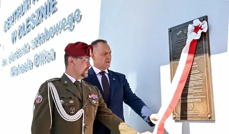 Prezydent RP Karol Nawrocki i kapitan rezerwy Wojska Polskiego Karol Cierpica podczas odsłonięcia tablicy w trakcie uroczystości nadania Centrum Kultury w Olesznie imienia sierż. sztabowego Michaela Ollisa.