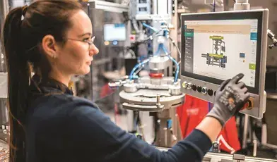 fabryka kobieta przy komputerze sterujacym robotem przemysłowym