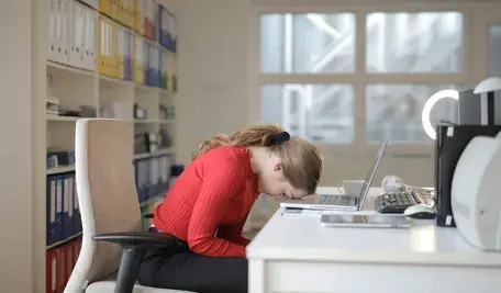 Załamana kobieta przed biurkiem.