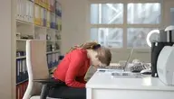 Załamana kobieta przed biurkiem.