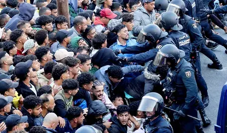 Tłum migrantów napierający w kierunku funkcjonariuszy hiszpańskiej policji podczas relokacji z plaży Benítez w Ceucie.