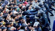 Tłum migrantów napierający w kierunku funkcjonariuszy hiszpańskiej policji podczas relokacji z plaży Benítez w Ceucie.