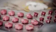 alt="Tabletki w blistrach farmaceutycznych na tle banknotów, ilustracja do tematu wyłudzeń refundacji leków z NFZ"