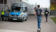 Mężczyzna na hulajnodze, w tle radiowóz policji