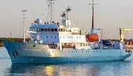 Statek badawczo-oceanograficzny Profesor Mołczanow (Профессор Молчанов) płynie po spokojnych wodach. Biało-niebieska jednostka z rosyjską nazwą na dziobie, wyposażona w nadbudówkę, maszty, łodzie ratunkowe i sprzęt badawczy, widoczna podczas rejsu w porcie