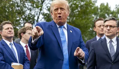 Donald Trump w niebieskim garniturze przemawia do dziennikarzy w otoczeniu polityków i liderów technologicznych przed Białym Domem.