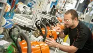 Linia produkcyjna pilarek. mężczyzna montuje elementy do maszyny
