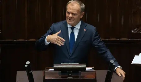 Donald Tusk z filiżanką kawy i gazetą „Rzeczpospolita” podczas nagrania, w którym mówi o wzroście polskiej gospodarki.