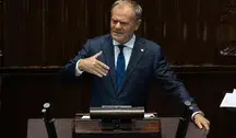 Donald Tusk z filiżanką kawy i gazetą „Rzeczpospolita” podczas nagrania, w którym mówi o wzroście polskiej gospodarki.