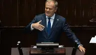 Donald Tusk z filiżanką kawy i gazetą „Rzeczpospolita” podczas nagrania, w którym mówi o wzroście polskiej gospodarki.